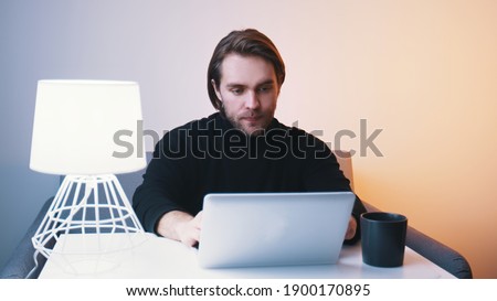Young caucasian man working on laptop at his home. Remote work concept. High quality photo
