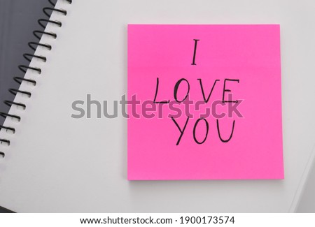 Memory sticker with phrase I Love You on notebook, top view. Valentine's Day celebration