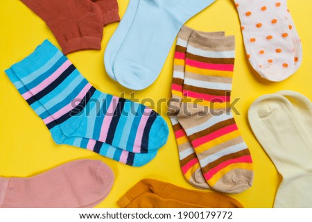 Multi-colored socks on a yellow background. View from above. Many different socks for cold seasons
