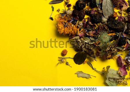 poured herbal collection from craft bag on yellow backdrop. medical tea from leaves, flowers and berries. place for text. close-up