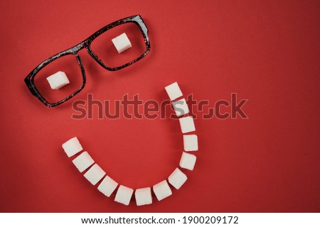 Smiling face made of sugar cubes on red background