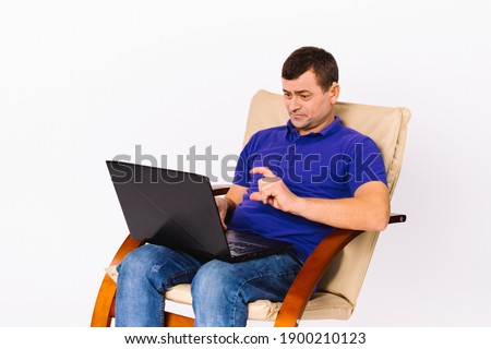 The deaf senior man sits in a leather armchair and communicates online on a laptop using non-verbal signs. White background.