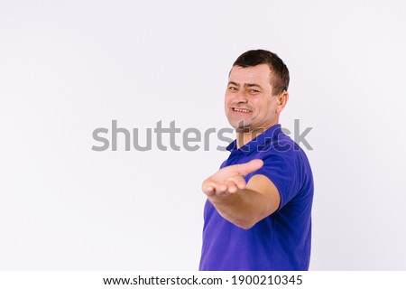 A surdomute man with a happy smile shows his empty hand to the camera. White background and empty side space.