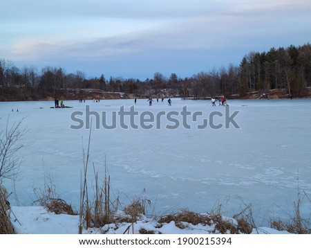 People ice skating and playing ice hockey on a lake