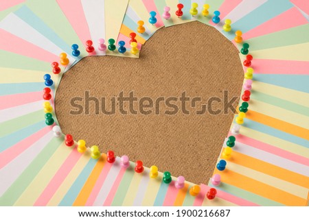 Close up photo of stickers and pins making shape of heart on the wooden board with empty space in center