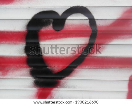 Heart in the graffiti style in black on a white wall and with red lines on the background