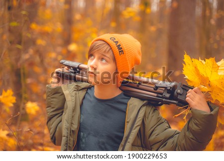 boy model posing in the autumn forest with a tripod in his hands