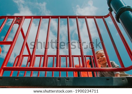 Happy kid sliding down the playground in a sunny day