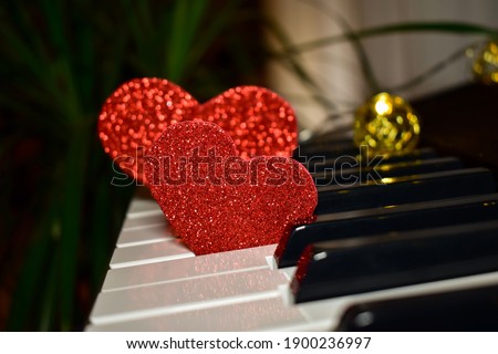 Red heart on piano keys, keyboard close up. Concept of love, valentine's day. Love background. Shallow depth of field, selective focus, blurred.