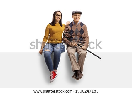 Grandfather and granddaughter sitting on a blank panel and smiling at camera isolated on white background Royalty-Free Stock Photo #1900247185