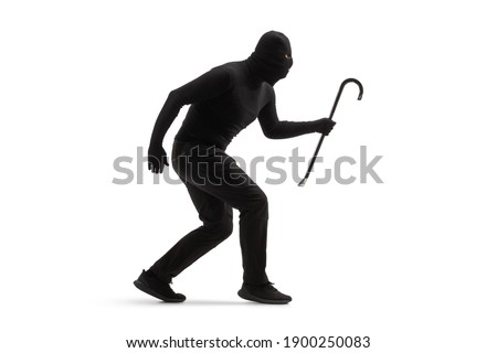 Full length shot of a burglar in black clothes with a balaclava and a crowbar walking slowly isolated on white background Royalty-Free Stock Photo #1900250083