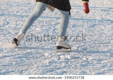 Women's feet in skates on an outdoor ice rink. Winter outdoor activities concept.