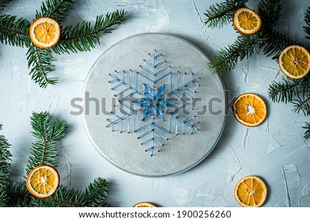 String art blue snowflake on a silver colored background with dried orange decoration