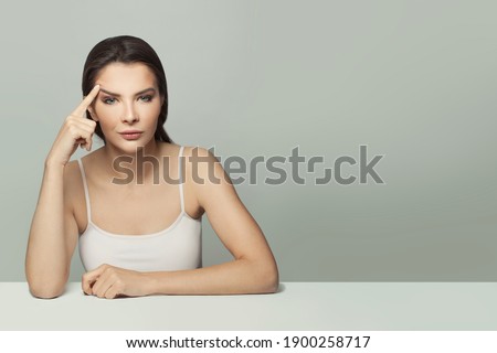 Pretty young woman sitting at white table portrait