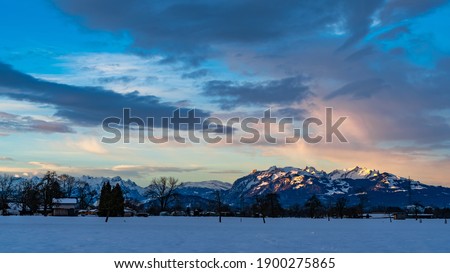 cloudy sunrise with colored clouds over the Swiss mountains. View from the valley of Rhein across the border into Switzerland. orange, red and blue sky. colors, dawn, illuminated snowy  summits