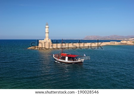Lighthouse in Chania, Crete, Greece, and a boat leaving the harbour
