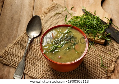 green broth with pepperoni and cabbage with top view on rustic wooden table
