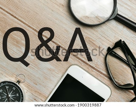 Top view compass,eye glasses,calculator,smartphone and magnifying glass with text Q AND A written on wooden background.Business concept.