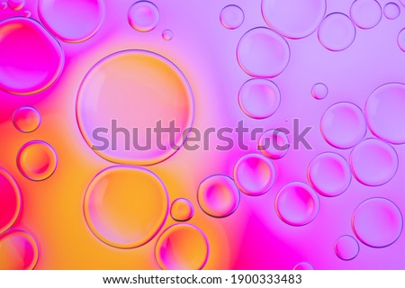 Creative neon background with drops. Glowing abstract backdrop with vibrant gradients on bubbles. Lilac, orange and pink overflowing colors