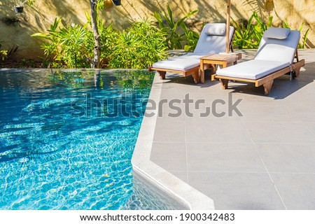 Umbrella and chair around outdoor swimming pool in resort hotel for vacation leisure Royalty-Free Stock Photo #1900342483