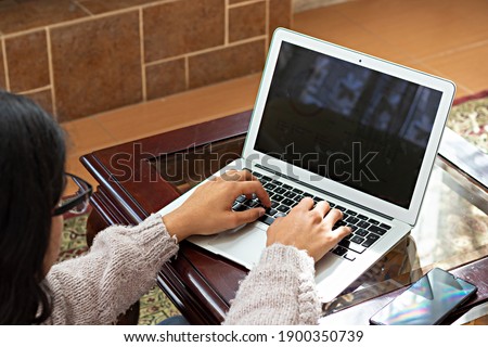 young man sitting in armchair, doing home office, typing on laptop