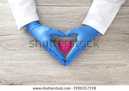 
Valentine's Day. heart in the hands of doctor with latex and female gloves, vintage wooden background for advertising baner Royalty-Free Stock Photo #1900357198