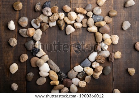 love concept image of heart shape frame made of round pebbles on wooden background
