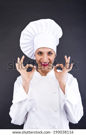 Attractive cook woman showing ok over dark background
