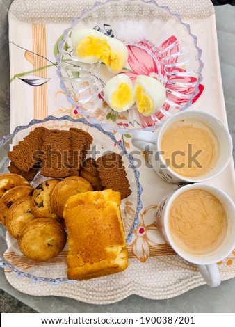 This is a picture of two cups of tea with biscuits and eggs