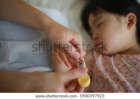 Mother cutting nails of sleeping girl