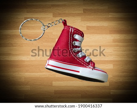 Miniature red baskeball shoe on wooden floor as background