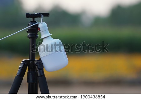 White electrical lamp hanging on camera tripod in the morning for selective focus and blurred background.Concept of relaxation and happy time.