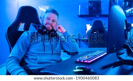Streamer young man rejoices in victory professional gamer playing online games computer with headphones, neon color. Royalty-Free Stock Photo #1900460083