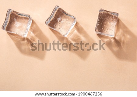 Three Ice cubes on pastel peach color background. Concept art. Minimal surrealism. Flat lay with copy space. Soft focus. Royalty-Free Stock Photo #1900467256