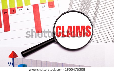 On the desktop, graphs, reports, a magnifying glass with the inscription CLAIMS. Business concept