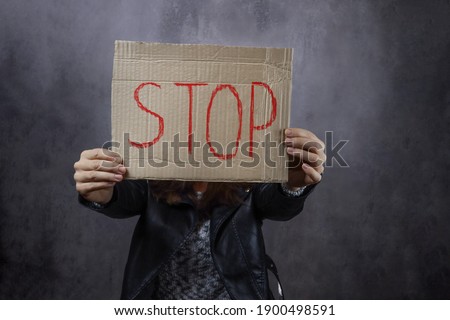 woman holding a piece of paper with the word Stop