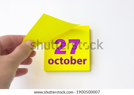 October 27th. Day 27 of month, Calendar date. Hand rips off the yellow sheet of the calendar. Autumn month, day of the year concept