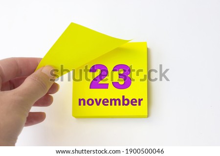 November 23rd. Day 23 of month, Calendar date. Hand rips off the yellow sheet of the calendar. Autumn month, day of the year concept