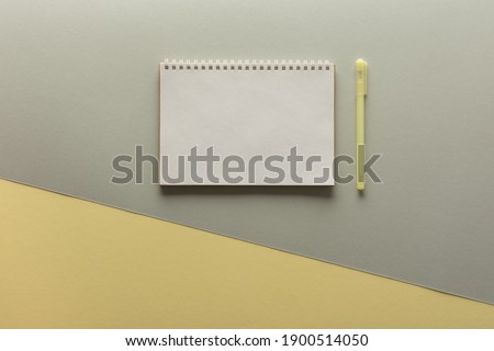 Open spiral notepad on gray and yellow background , notebook and pen lie on textural paper, flat lay concept in trendy colors of the year yellow and gray