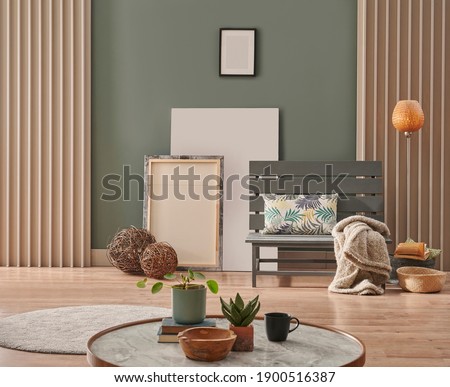 Green wall, grey chair with marble pattern middle table, frame, round carpet, pillow and orange lamp design.