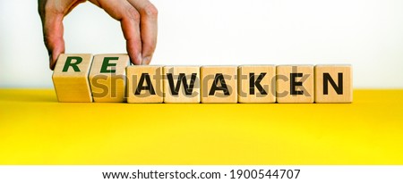 Reawaken symbol. Businessman turns cubes and changes the word 'awaken' to 'reawaken'. Beautiful yellow table, white background, copy space. Business and reawaken or awaken concept.