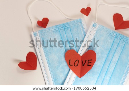 
red heart on a mask on valentine's day on a white isolated background. heart surgical mask with place for inscription, mock up, copy space