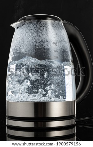 glass electric kettle with boiling water on a dark background
