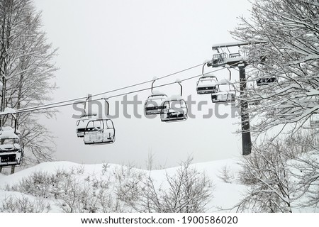 chairlift without people in cloudy winter environment with fresh snow