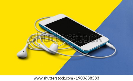 smartphone with earphone on isolated yellow, blue background