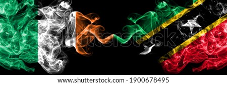 Republic of Ireland, Irish vs Saint Kitts and Nevis smoky mystic flags placed side by side. Thick colored silky abstract smoke flags.