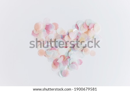 Happy Valentines day. Colorful confetti in heart shape on white background, flat lay with copy space. Party celebration and love concept. Simple tender image