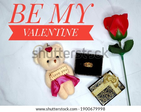 Selective focus of red rose, a key chain teddy bear with word i love you, gold ring and box with text be my valentine. Happy valentine's day concept.