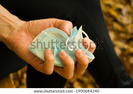 Medical mask crumpled, squeezed and wrinkled by female hand, close up