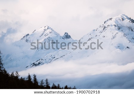 Foggy winter mountain landscape. Panoramic view of mountains near Brianson, Serre Chevalier resort, France. Ski resort landscape. Snowy mountains. Winter vacation. Misty morning in mountains